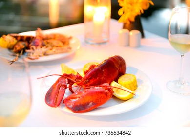 Luxury Romantic Candle Light Dinner Setup By The Pool With Plate Of Lobster And Seafood BBQ