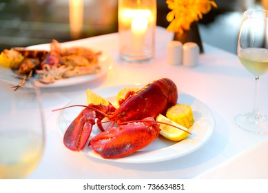 Luxury Romantic Candle Light Dinner Setup By The Pool With Plate Of Lobster And Seafood BBQ