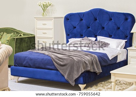 Luxury royal bedroom in antique style with blue velvet bed and white nightstand.