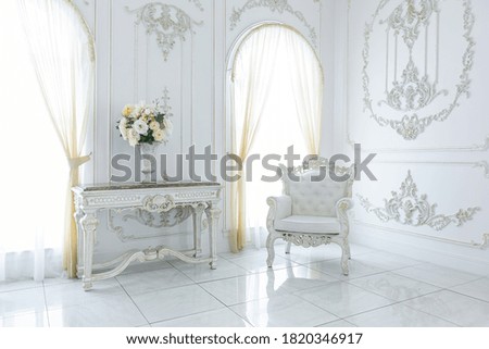 luxury royal posh interior in baroque style. very bright, light and white hall with expensive oldstyle furniture. large windows and stucco ornament decorations on the walls