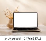 Luxury scene with laptop on the table and vase with bouquet, aesthetic sunlight shadows. Laptop with white screen for website, blog, social media and branding.