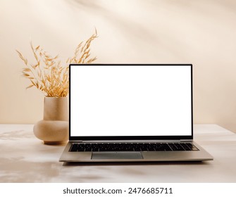 Luxury scene with laptop on the table and vase with bouquet, aesthetic sunlight shadows. Laptop with white screen for website, blog, social media and branding.