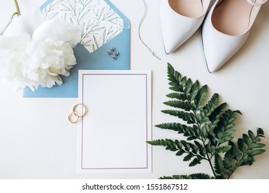 Luxury set of wedding invitations, wedding rings, elegant accessories of the bride on a white background. Blue paper envelope for invitation.