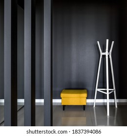 Luxury And Simple Corridor Interior With Modern Black Wall, White Clothes Hanger And Yellow Ottoman Seat