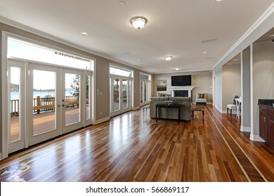 Luxury spacious family room interior with wall of glass doors leading out to spacious deck and facing the lake, polished hardwood floor and cozy sitting area with fireplace . Northwest, USA