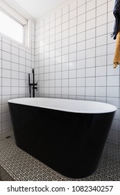 Luxury Stand Alone Black Bathtub In A Dully Tiled Bathroom