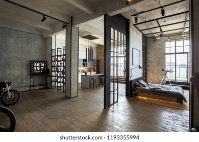 luxury studio apartment with a free layout in a loft style in dark colors. Stylish modern kitchen area with an island, cozy bedroom area with fireplace and personal gym - Shutterstock ID 1193355994