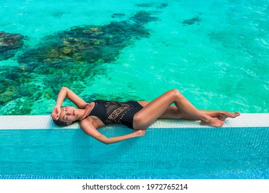 Luxury Suntan Beauty Asian Swimsuit Model Woman Lying Down Sunbathing On Idyllic Infinity Swimming Pool Travel Bikini Girl Vacation Sun Tan Over Turquoise Ocean In Bora Bora Tahiti, French Polynesia.