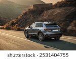 A luxury SUV cruising along a scenic mountain road during golden hour, capturing the dynamic and sleek design of the vehicle with warm lighting and natural surroundings