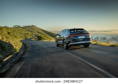 Luxury SUV driving on a scenic mountain road with a city view, ideal for travel promotions, road trip articles, or car advertisements.