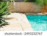 Luxury swimming pool with tropical plants and stone path. Poolside patio in mediterranean holiday villa.