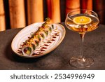 A luxury table features two elegant pieces of sushi, garnished with fresh herbs and a glass of white vermouth.