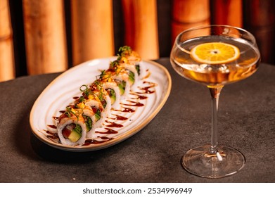 A luxury table features two elegant pieces of sushi, garnished with fresh herbs and a glass of white vermouth.