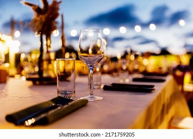 Luxury Table Settings For Fine Dining With And Glassware, Pouring Wine To Glass. Beautiful Blurred Background. Preparation For Holiday Wedding. Fancy Luxury Restaurant.