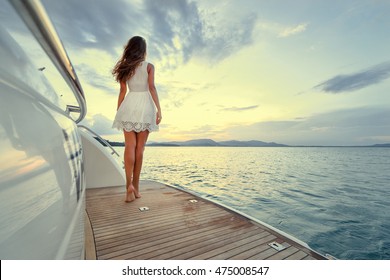 Luxury travel on the yacht. Young woman enjoying the sunset on boat deck sailing the sea.
