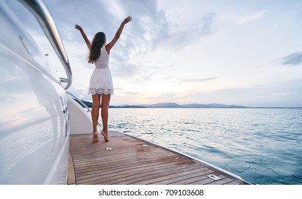 Luxury Travel On The Yacht. Young Woman Enjoying The Sunset On Boat Deck Sailing The Sea.