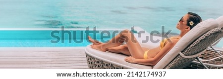 Luxury travel vacation in paradise high end resort hotel bikini woman relaxing lying on lounger sunbathing by the swimming pool at overwater villa suite. Laser waxing legs hair removal concept