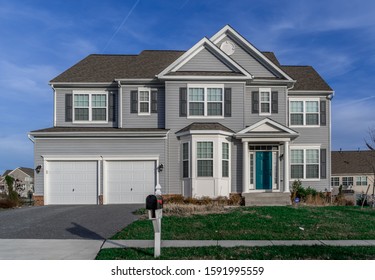 Luxury Upscale American Single Family Estate Home With Vinyl Siding, Double Car Garage Door, Covered Porch, Bay Window, Double Gable Roof With White Round Louver Vent, Hung Sash Windows In The USA