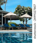 Luxury vacation, poolside, pool umbrellas, pool chairs, pool deck, resort, white tropical flowers, vacation, travel, spa, all inclusive resort, luxury hotel, luxury beach hotel with pool, beachfront