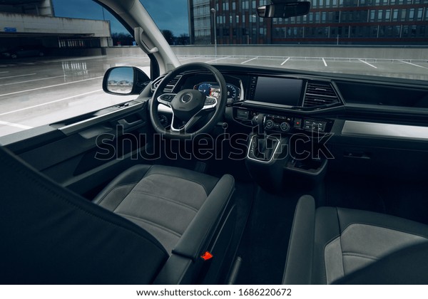 Luxury van driver seats with dashboard,\
multimedia control screen, and steering wheel. Wide-angle view on\
modern var interior