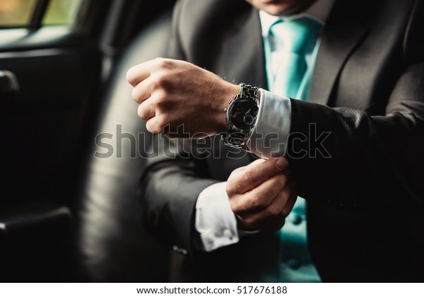 Luxury watch on hand of elegant man in a business\
suit sitting in the car