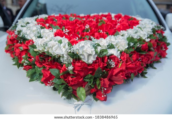 Luxury wedding car decorated with\
flowers . White, red heart bouquet on white bridal car. Wedding car\
and petals on top. Luxury wedding car decorated with\
flowers.