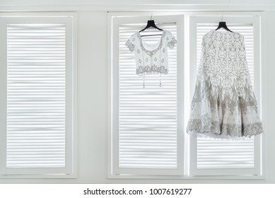 Luxury wedding dress saree (shari) and blouse of indian bride hanging on the white wall windows with light