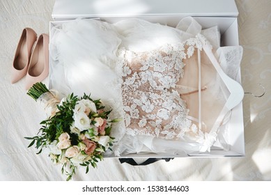 Luxury wedding dress in white box, beige women's shoes and bridal bouquet on bed, copy space. Bridal morning preparations. Wedding concept - Powered by Shutterstock