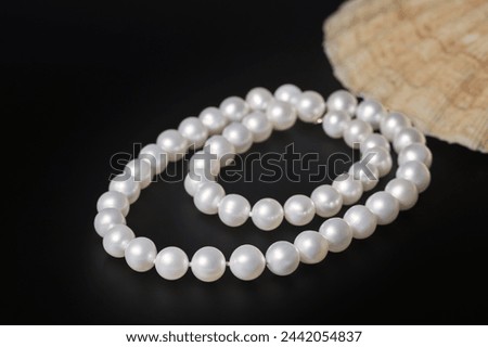 luxury women's necklace made of white sea pearls on a black matte background , the concept of beauty and fashion