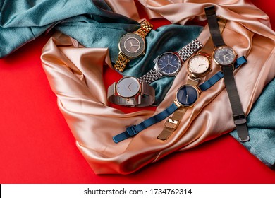 Luxury Wrist Watches With Light Pink And Blue Silk Fabric On Red Color Background. Gold Watch. Women And Man Watches. Female And Male Watches. Closeup. Fashion Accessory