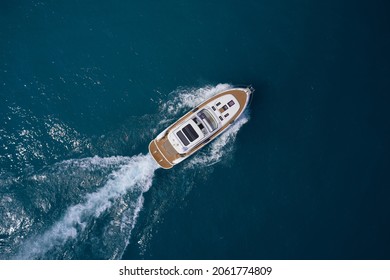 Luxury yacht on the water aerial view. White yacht fast movement on the water top view. Travel - image. Top view of a white high-speed boat. Yacht movement on blue water top view.