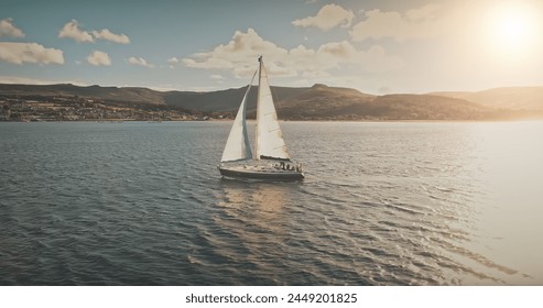 Luxury yacht race at sun light aerial. Yachting on serene seascape at open sea. Boat with big white spinnaker sail at ocean bay. Lonely ship cruise at water on summer sunny day. Cinematic drone shot - Powered by Shutterstock