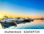 Luxury yachts docked in sea port at sunset. Marine parking of modern motor boats and blue water. Tranquility, relaxation and fashionable vacation.