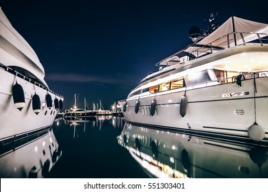 Luxury yachts in La Spezia harbor at night with reflection in water. Italy - Powered by Shutterstock