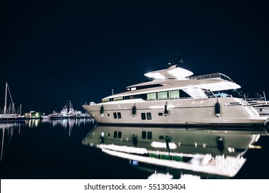 Luxury yachts in La Spezia harbor at night with reflection in water. Italy