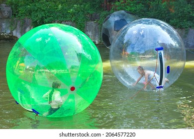 Lviv Ukraine - 07 25 2021: Fun game on the water zorbing, children swim and have fun in a transparent inflated plastic balloon, active pastime on vacation
