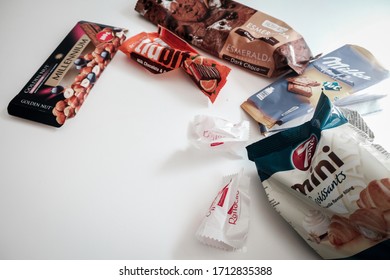 Lviv / Ukraine - April 2020: Assorted candy, cookie and chocolate wrappers left on a white table. Delicious sweets full of sugar that leads to health issues and overweight. Binge eating in isolation.