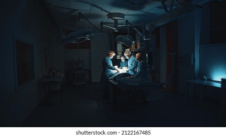 Lviv, Ukraine - February 8, 2022: Doctors In Uniform Perform Surgery In The Operating Room On Dark Background. Operation In Modern Hospital. Innovation Technology System. Professional Doctor Group.