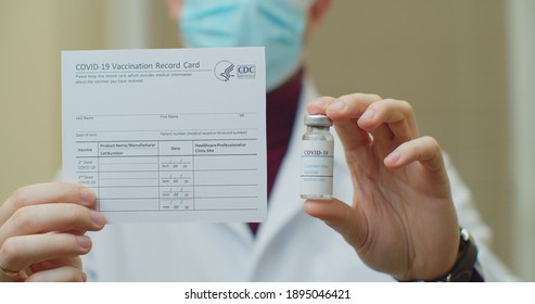 Lviv, Ukraine - January 14, 2021: Doctor Is Holding A Vaccination Record Card And Corona Virus Vaccine Vials. Passport Of Immunity To The Coronavirus In The Hands Of A Male Doctor. Health Passport As