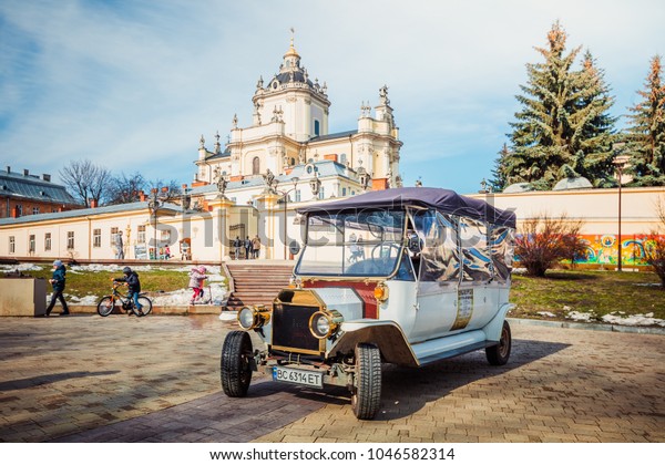 Lviv, Ukraine - March 8, 2018: Retro\
sightseeing car near St. George Cathedral in\
Lviv