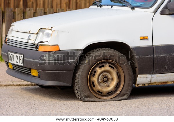 Lyckeby, Sweden - April 7,\
2016: White 1990 Renault GTS with a flat front tire standing at\
roadside.