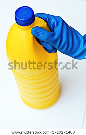 
Lye bottle gripped by blue rubber glove