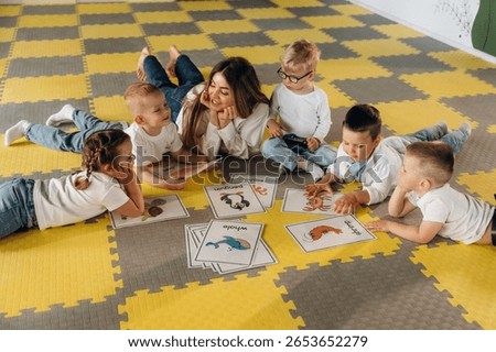 Lying down on floor, learning new words. Children in kindergarten with their teacher.