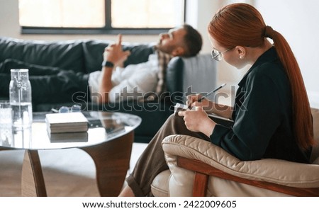 Lying down on the sofa. Man is on the therapy session with female psychologist.