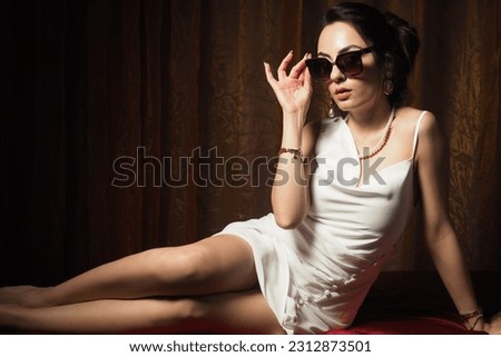 Lying down pose of sexy, young, beautiful, long hair, brunette,  charming woman in white dress. Shot inspired by boudoir poses
