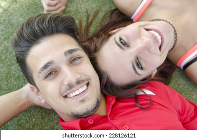 Lying face up couple on grass smiling and looking at camera