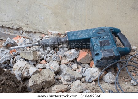 lying HammerDrill in the construction tool on a pile of bricks and stones