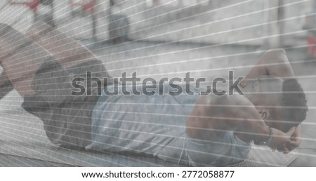 Lying man performing crunches on bench by graffiti wall, wearing tank top and dark shorts. Outdoor, urban, fitness, workout, core, motivation, endurance