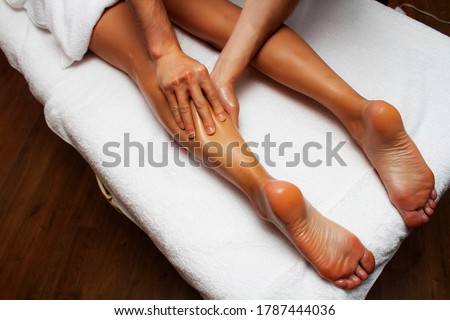 Lymphatic drainage massage of legs and lower legs. Female feet in the hands of a masseur.
