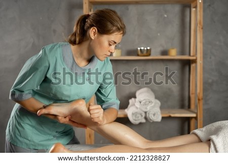 Lymphatic drainage massage of legs and shins. Female feet in the hands of a masseur.Leg massage treatment in the spa salon. A woman receiving a holistic massage treatment.